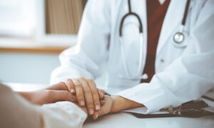 Woman doctor holding hands of patient